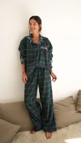 Conjunto de pijama a cuadros con ribetes en color lila, compuesto por camisa de manga larga con botones y pantalón largo.
