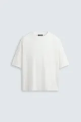 Camiseta de algodón de peso ligero, color blanco roto con efecto lavado, corte boxy fit, cuello redondo y manga corta.