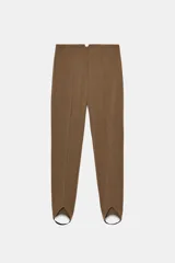 Pantalón de tiro alto color marrón, con nervio frontal marcado y bajo acabado en estilo fuseau (con tira elástica para pasar por debajo del pie).