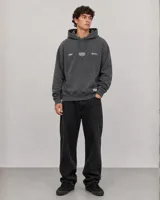 Canguro con capucha y cordones ajustables, de color gris oscuro con efecto lavado. Presenta un bolsillo frontal tipo canguro y estampado gráfico pequeño en el pecho con el logo de la marca.