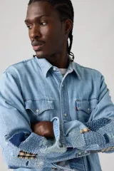 Camisa de jean estilo western con diseño de parches tipo sashiko en las mangas. Presenta cuello clásico, cierre frontal con botones a presión, dos bolsillos en el pecho con solapa y puños abotonados.