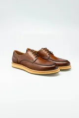 Zapato acordonado de cuero marrón con suela de goma color beige.