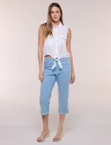 Camisa sin mangas de rayón texturado color blanco, de corte crop con cierre frontal de botones y lazos para anudar en el frente. Cuenta con cuello camisero, detalles de brillos en los hombros y bolsillos plaqué con solapa en el pecho.