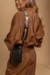 Bandolera compacta color rojo con textura de cuero, correa regulable y desmontable con diseño de rayas rojas y blancas. Cuenta con bolsillos frontales y cierre, interior forrado en tela.