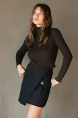 Falda corta color verde militar, estilo wrap o cruzada, con un bolsillo tipo parche con fuelle y un botón decorativo en el frente.