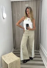 Pantalón de jean negro de pierna ancha con cortes laterales y godets triangulares en tela de broderie o encaje color crudo para mayor amplitud.