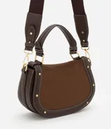 Cartera bandolera de tamaño mediano con cuerpo frontal en gamuza y laterales rígidos. Cuenta con asa corta superior, correa larga ajustable y desmontable, y bolsillo trasero. Presenta detalles metálicos en los bordes.