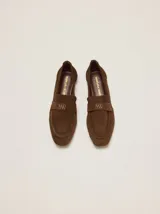 Mocasines de gamuza marrón, con punta fina, costuras visibles y detalle bordado en el empeine.