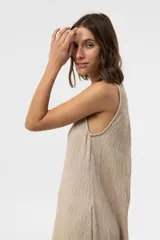 Vestido midi sin mangas de color marrón, confeccionado con textura arrugada, escote redondo, silueta relajada y caída liviana, con un lazo fino ajustable en la cintura.