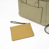 Cartera tipo tote de cuero sintético color verde con doble asa de mano y correa larga desmontable. Tiene un bolsillo frontal con cierre y detalle de tira decorativa.