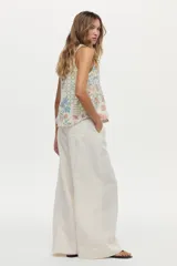 Musculosa de lino y viscosa, de color crudo con estampado multicolor de inspiración veraniega con flores, soles y motivos marinos. Presenta escote redondo y diseño sin mangas.