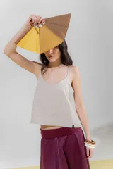 Top de lino color beige con escote en V y breteles regulables con detalle de borlas. Calce recto con un leve evasé y largo a la cadera con terminación recta.