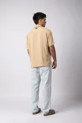 Camisa de manga corta con cuello cubano, confeccionada en lino entramado de textura natural. Presenta un corte relajado y cierre frontal con botones.