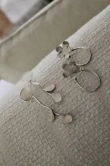 Aros colgantes plateados con forma de rama con hojas y círculos.