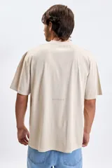 Remera de manga corta con corte oversize, color beige, con cuello redondo y estampado sutil en el centro del pecho.