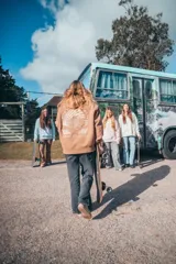 Canguro marrón con capucha y cordones ajustables. Presenta un estampado grande en la espalda con una ola, palmeras y el texto "Glassy Waves".