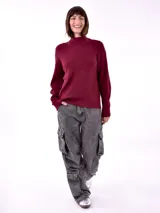 Buzo de tejido de punto en color bordó, con cuello alto y mangas largas con puños acanalados.