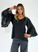 Blusa de algodón color negro, con escote en V y mangas largas amplias terminadas en volados escalonados.