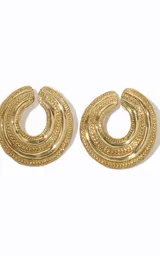 Aros de metal dorado con diseño orgánico calado, estructura en capas y textura en relieve.