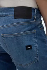 Jean de denim azul con calce recto y pierna amplia de caída relajada, tiro bajo y bolsillos clásicos.