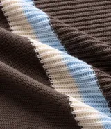 Suéter de punto texturizado con diseño de rayas horizontales en tonos marrón, crema y celeste. Presenta cuello polo con abertura frontal, mangas largas y terminaciones acanaladas en puños y dobladillo.