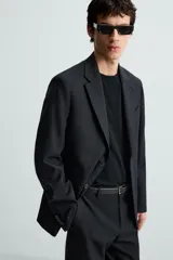 Blazer de corte regular fit confeccionado en tejido con lana. Presenta cuello con solapas de muesca, cierre frontal de dos botones, manga larga con puños abotonados, bolsillo de vivo en el pecho y bolsillos con solapa en la cadera.
