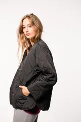 Campera capitoneada color verde oliva, con cuello redondo, cierre frontal con botones a presión, bolsillos laterales y aberturas laterales con botones.