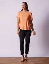 Remera blanca texturada con cuello redondo y mangas cortas con dobladillo. Detalle de botones en la espalda.