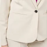 Chaqueta sastre de corte clásico en color beige, con solapas de muesca, cierre frontal de un botón y bolsillos laterales con solapa.