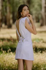 Vestido corto blanco con solapas tipo sastre, sin mangas y con bolsillos laterales.