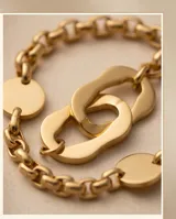 Pulsera de acero con baño de oro, compuesta por una cadena de eslabones finos y un dije central de eslabones ovalados entrelazados.