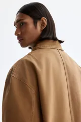 Campera de algodón color marrón con cuello camisero, cierre frontal, bolsillo superior con cierre y bolsillos laterales ribeteados.