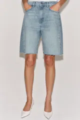 Bermuda de denim color marrón oscuro, de tiro medio y diseño relaxed fit, con cinco bolsillos, trabillas para cinto, bajo desflecado y cierre frontal con cremallera y botón.