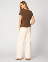 Remera blanca de manga corta con cuello redondo, confeccionada en una mezcla de modal, poliéster y elastano. Presenta un diseño con alforzas verticales en el frente que aportan estructura y una silueta relajada.