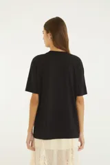 Remera negra de algodón con cuello redondo, mangas cortas y estampa frontal de paisaje playero con la inscripción "Carioca".