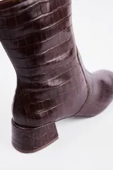 Bota de caña media con textura de reptil, color negro, con taco cuadrado bajo y punta redondeada.