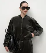 Campera bomber de terciopelo color verde oscuro, con cuello redondo, cierre frontal con botones metálicos, bolsillos laterales y mangas largas con puños elásticos.