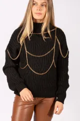 Sweater de punto grueso color negro, con cuello alto y diseño de cadenas doradas decorativas integradas en la parte frontal y hombros.