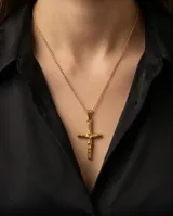 Dije de cruz en acero dorado con relieve de la figura de Cristo.