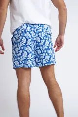 Short de baño con cintura elástica y cordón ajustable, confeccionado en tela ligera de secado rápido. Presenta un estampado botánico integral en tonos amarillos, blancos y azules, con dos bolsillos delanteros y uno posterior.