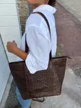 Bolso tote de cuero natural color beige, con doble asa de hombro, costuras visibles y cierre de broche.