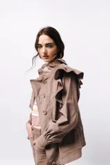 Campera de pana color blanco, de corte oversize, con cuello alto, cierre frontal de botones y volados decorativos en los hombros y cuello.