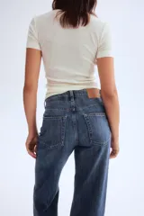 Pantalón de jean azul de tiro alto, corte ancho y largo hasta el tobillo. Confeccionado en denim de algodón rígido con cinco bolsillos, cierre frontal con cremallera y botón. 