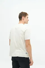 Remera de manga corta color beige con estampado fotográfico en el pecho. Presenta un corte regular y cuello redondo.