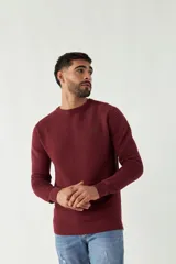 Sweater color borgoña de punto con textura acanalada horizontal y logo bordado en el pecho. Corte slim fit, cuello redondo y mangas largas con puños.