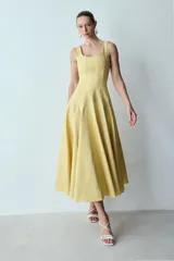 Vestido midi amarillo pálido sin mangas, con escote cuadrado, corte ajustado en el torso y falda acampanada.