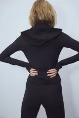 Campera deportiva de corte ajustado confeccionada en tejido funcional con tecnología SoftMove y DryMove. Presenta capucha, cierre frontal con protección para el mentón, bolsillos laterales con cierre y mangas extralargas con abertura para el pulgar.