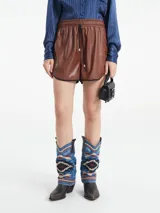 Short de cuerina color marrón con elástico en la cintura y terminaciones con vivos negros.