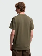 Remera de algodón en color verde oliva, de corte clásico con cuello redondo y manga corta. Presenta un parche bordado con el logo de la marca en el pecho.