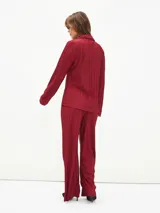 Camisa negra con textura plisada, cuello clásico, escote en V y mangas largas.